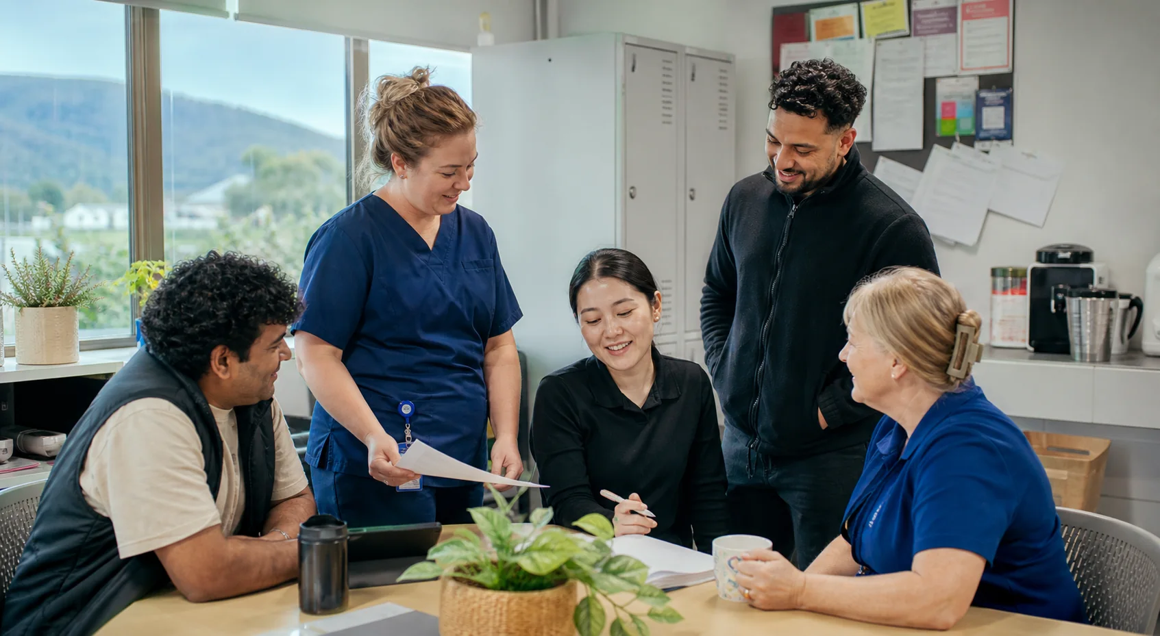 A diverse care team reviewing a shift handover together in a community-care office