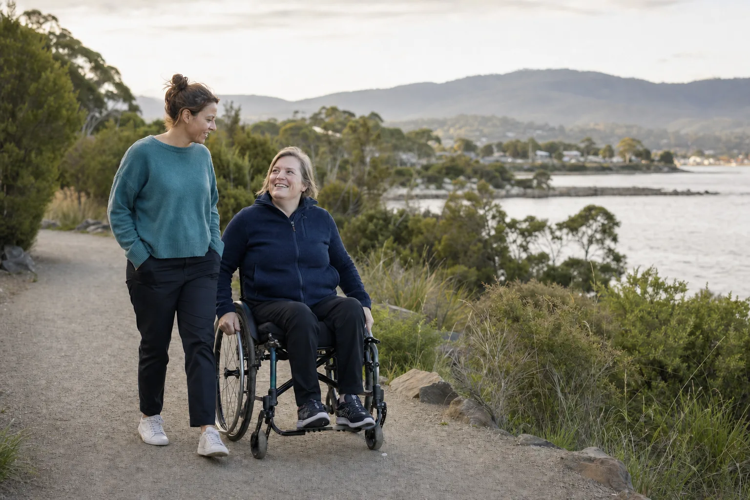 A wheelchair user and support worker enjoying a Tasmanian coastal path
